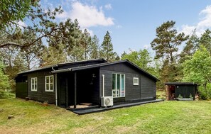 A log cabin with a porch, a small shed, and a grassy yard surrounded by trees. - 3 bedroom amazing home in Rømø (Rømø)