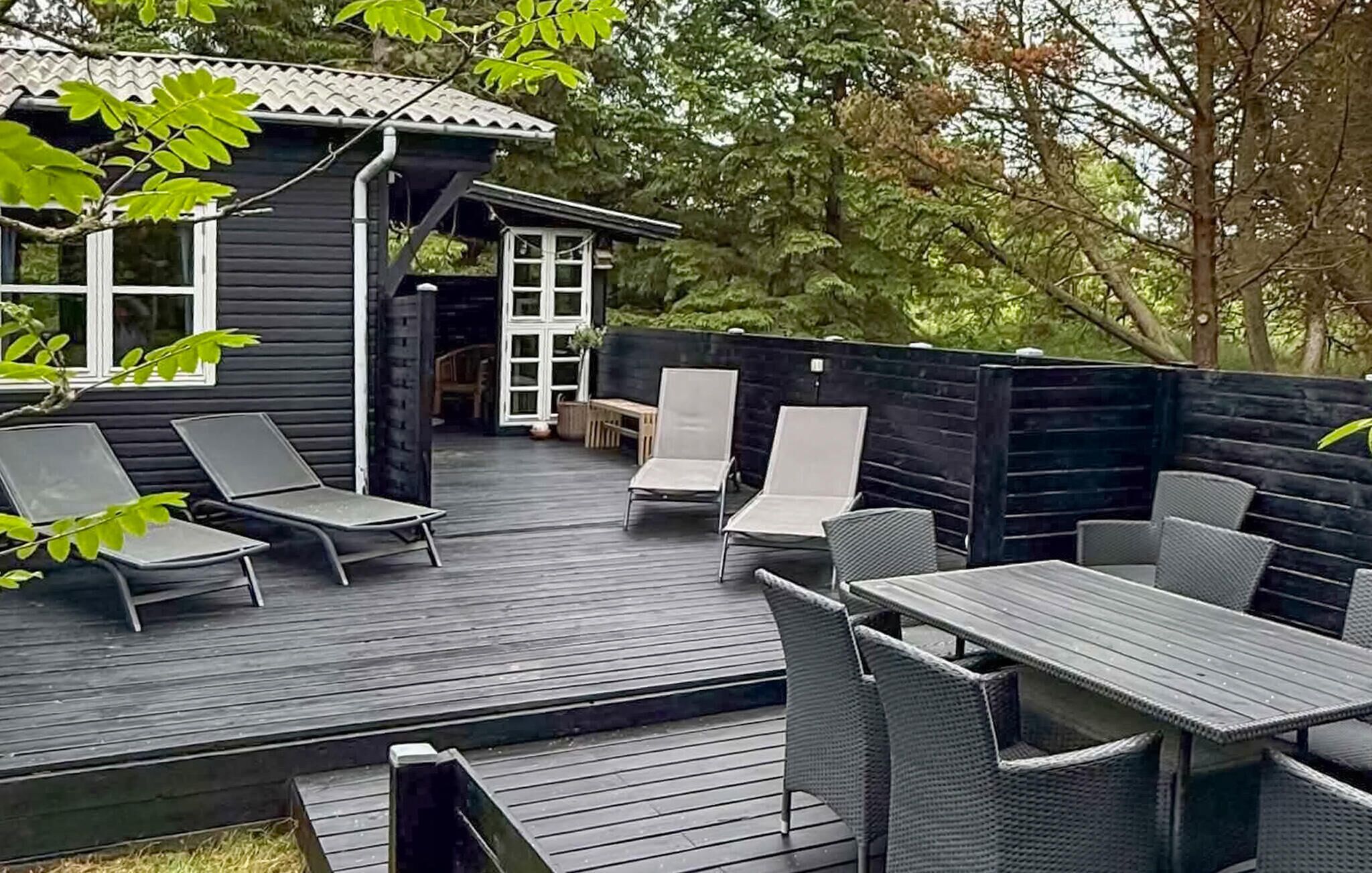 A deck with outdoor furniture, a small building with windows, and a wooden fence.
