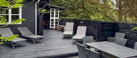 A deck with outdoor furniture, a small building with windows, and a wooden fence.