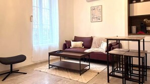 A living room with a sofa, a coffee table, a bench, and a chandelier. - Le loft sur rivière (Dijon)