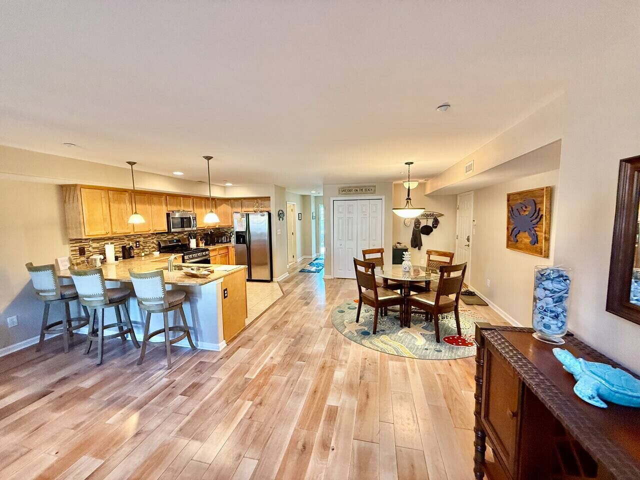 A spacious kitchen with wooden flooring, a dining area with a round table and chairs, and a kitchen island with bar stools.