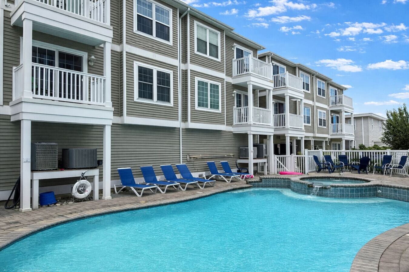 A multi-story residential building with a swimming pool, outdoor seating, and balconies.