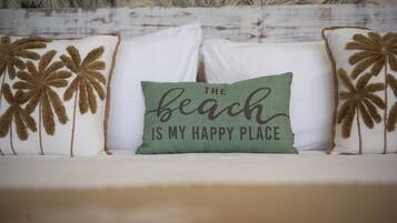 A bed with white bedding and decorative pillows with palm tree designs.