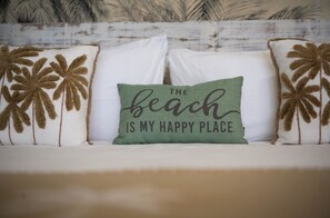 A bed with white bedding and decorative pillows with palm tree designs. - Matira Lagoon (Bora Bora)