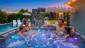 Ett bubbelbadkar för fyra personer, omgivet av utomhusmöbler och en pool.