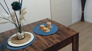 Une table en bois ornée d’un vase de fleurs blanches et d’un objet décoratif comprenant des tasses en bois et une bougie.