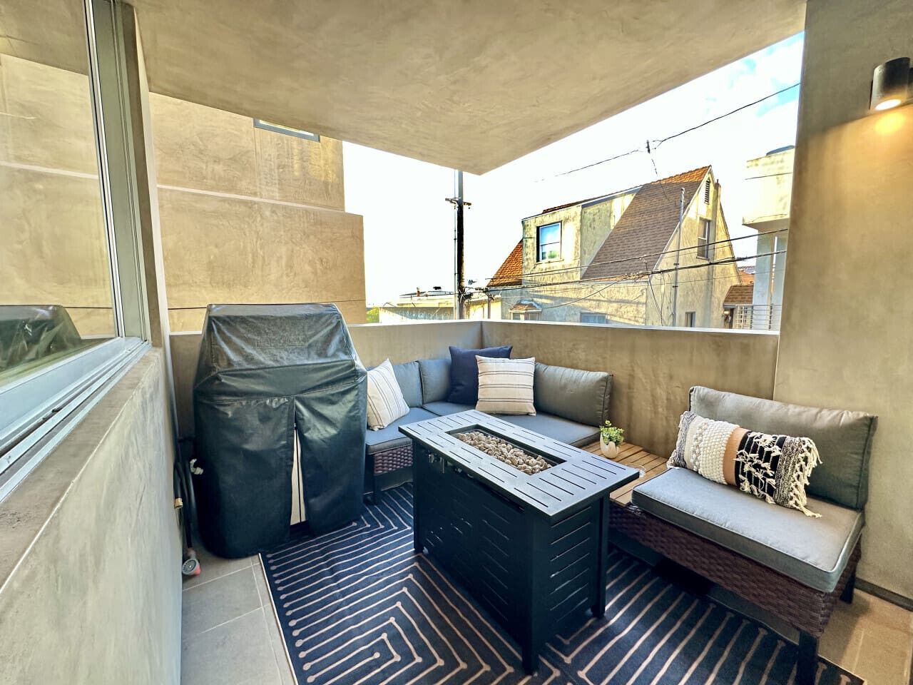 A balcony with a sofa, a small table, and a covered grill.