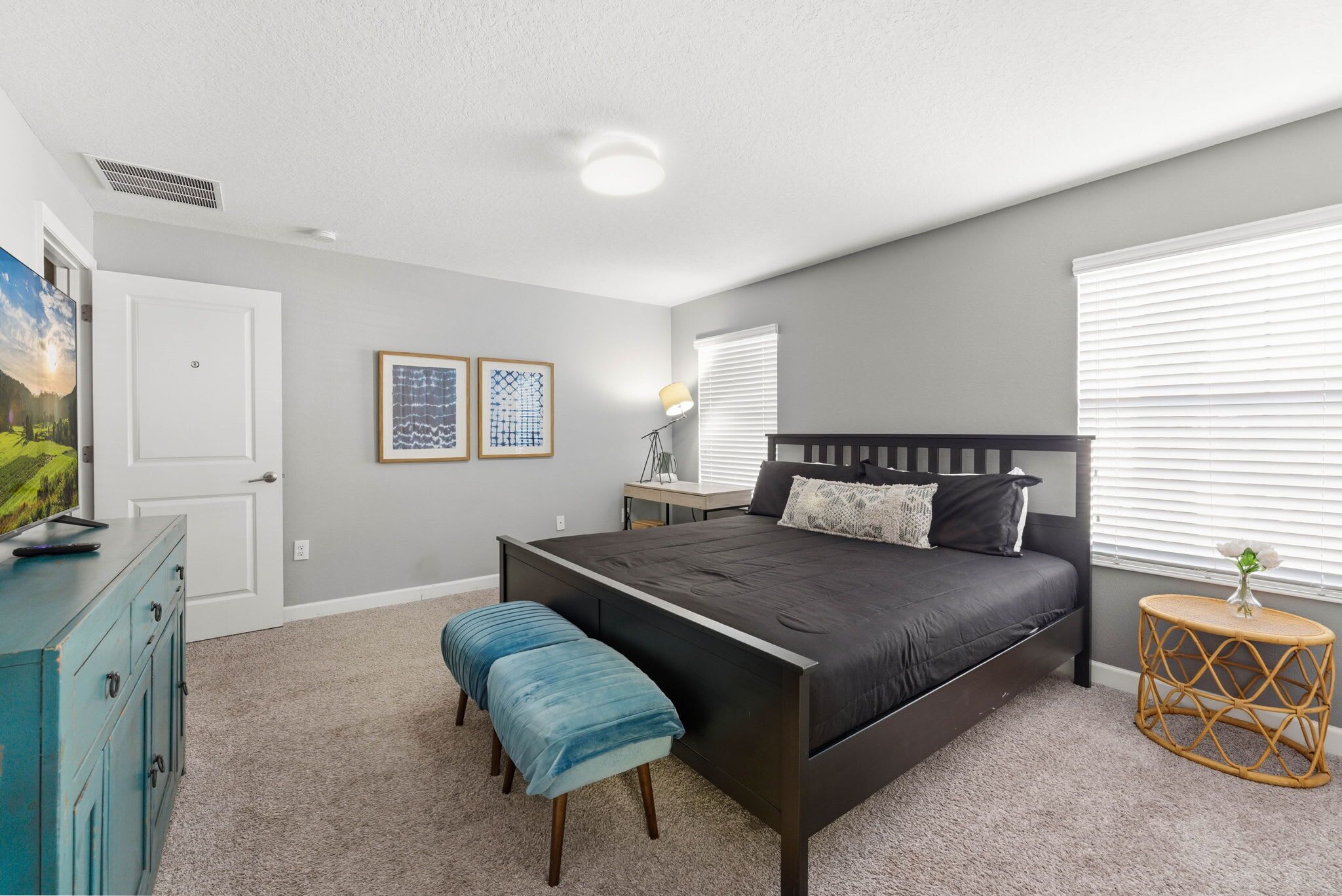 A bedroom with a bed, bench, dresser, and bedside table.