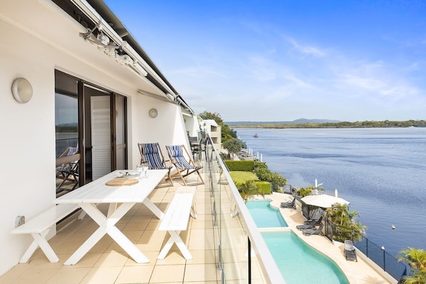 Ein Balkon mit Pool, Liegestühlen und Tisch.