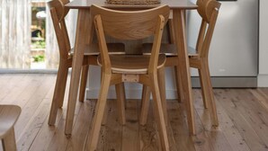 A wooden dining table with four chairs in a modern kitchen with white walls and a view of greenery outside. - Prickly Pear Stays in Merewether - Ridge St (Merewether)