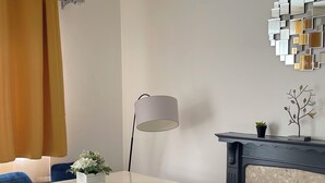 Ein moderner Essbereich mit einem weißen Tisch, blauen Stühlen, einer Stehlampe und einem Kamin.