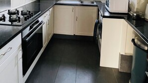 Eine kompakte Küche mit Gasherd, Backofen, Mikrowelle und Spüle. Ein Fenster sorgt für natürliches Licht und bietet einen Ausblick nach draußen.