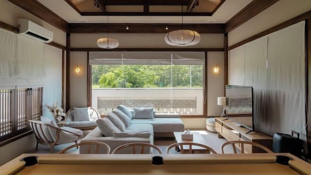 Een moderne woonkamer met een bank, stoelen, een televisie en een eethoek.