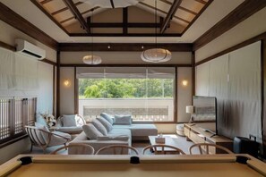 A modern living room with a sofa, chairs, a TV, and a dining area. - Krajokkaew Inyeon Khao Yai (Pak Chong)