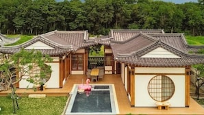 Een traditioneel Japans gebouw met pannendak, een kleine binnentuin en een kiezelpad dat leidt naar een houten deur.