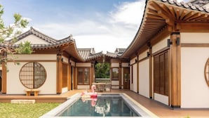 Een traditioneel Japans gebouw met een zwembad, houten vloeren en een houten omheining.