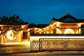 Un bâtiment traditionnel doté d’un toit incurvé et de fenêtres illuminées la nuit.