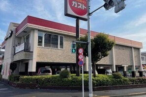Un bâtiment avec un toit rouge, une enseigne avec des caractères japonais et un panneau indiquant qu’il est interdit de se garer.