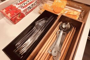 Un tiroir contenant un ensemble de couverts, notamment des fourchettes, des couteaux et des cuillères, ainsi que des baguettes en bois.