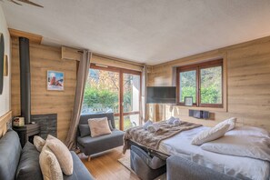 Een gezellige slaapkamer met een bed, een bank, een televisie en een open haard.