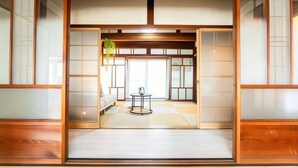 Una habitación japonesa tradicional con suelo de tatami, puertas correderas y una mesita con una planta.