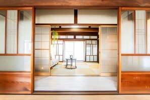 A traditional Japanese room with tatami flooring, sliding doors, and a small table with a plant. - Nagashima Traditional House (Kuwana)