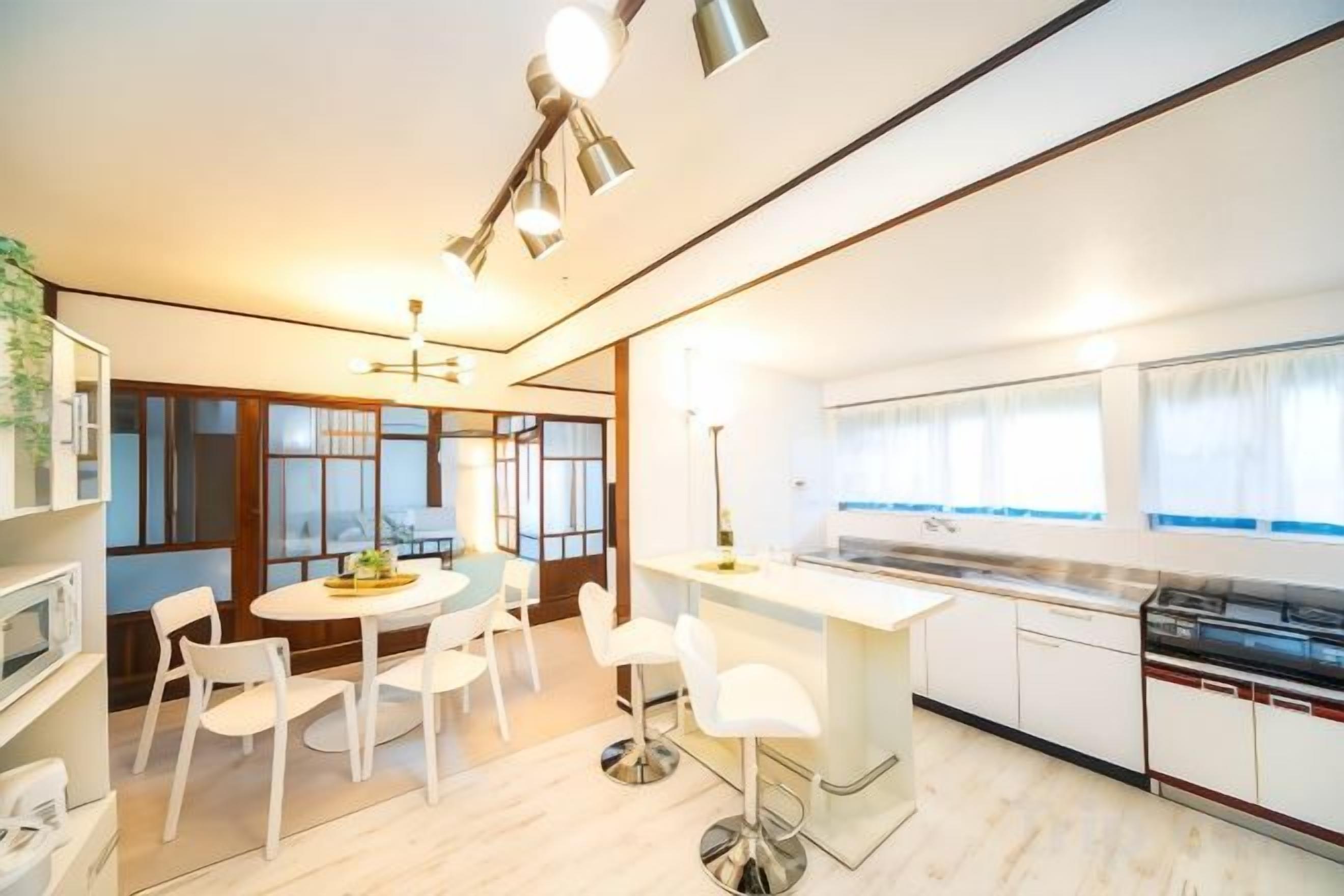 A modern kitchen with white cabinetry, a dining area with a round table, and a view of the city through large windows.