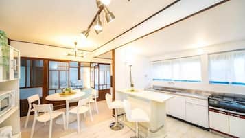 A modern kitchen with white cabinetry, a dining area with a round table, and a view of the city through large windows.