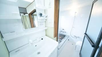 A bathroom with a sink, mirror, and shower area.