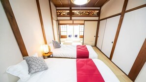 Una habitación tradicional japonesa con dos camas, cada una con almohada y mesita de noche con lámpara.