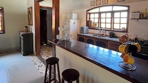 A kitchen with a wooden ceiling, a bar area with stools, and a window with decorative frames. - House with pool and 4 suites in Bertioga (Bertioga)