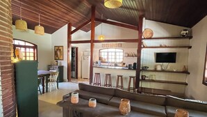 A spacious living area with a high ceiling, exposed wooden beams, and a central seating area. - House with pool and 4 suites in Bertioga (Bertioga)