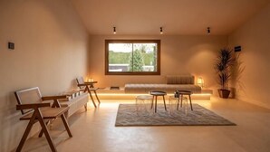 A modern living room with a large window, a sofa, a coffee table, and a potted plant. - All About Santa Ana Villa (Marbella)