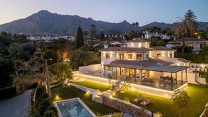 A modern house with a swimming pool, a covered patio, and a view of mountains. - All About Santa Ana Villa (Marbella)