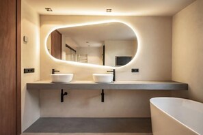 A modern bathroom with two sinks, a large mirror, and a bathtub. - All About Santa Ana Villa (Marbella)