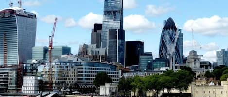 A city skyline with modern buildings, a river, and a boat.