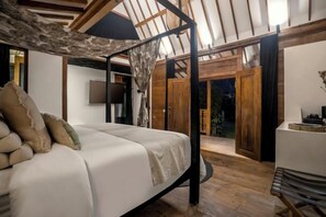 Een slaapkamer met hemelbed, flatscreen televisie en een houten deur naar een balkon.