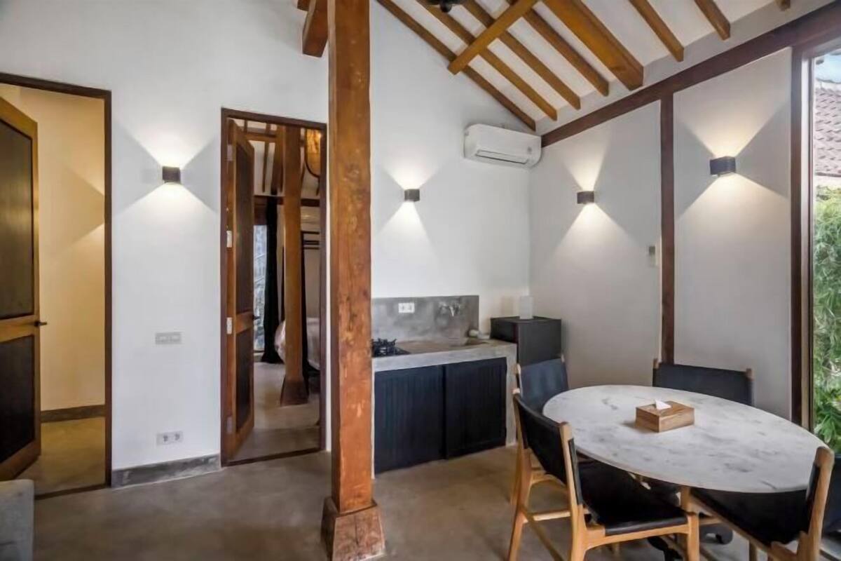 A modern kitchen with built-in appliances, a dining area with a marble table, and a wooden ceiling structure.