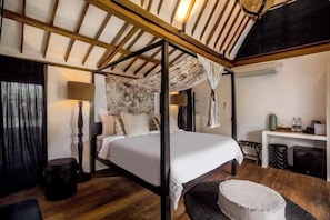 Un lit à baldaquin, un bureau avec une chaise et une petite table ronde avec une lampe.