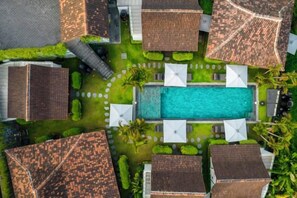 Luchtbeeld van een resort met een centraal zwembad, omringd door meerdere bungalows met privéterrassen.