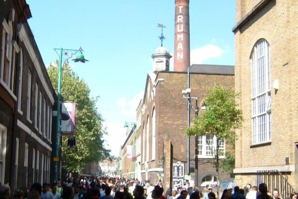 A busy street with historic buildings, including a prominent chimney labeled 'TRUMAN.' - 3VH Virginia House, 31 Bloomsbury Way by City Living London (London)