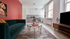 A modern living room with a green sofa, a coffee table, and a flat-screen TV. - 3VH Virginia House, 31 Bloomsbury Way by City Living London (London)