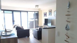 A modern apartment with a kitchen, dining area, and a large window. - Sails Unit 25 (Sunshine Coast)