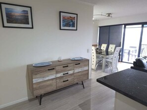 Een moderne keuken met een houten kast, een zithoek met een glazen tafel, en een balkon met uitzicht.