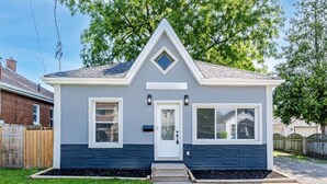 A single-story house with a gabled roof, a front door with a small porch, and a window on the right side. - The Millertime Den (Brantford)
