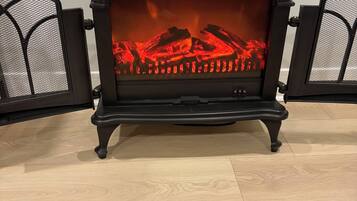 Un poêle à bois noir, doté d’une porte en verre, posé sur un plancher en bois.