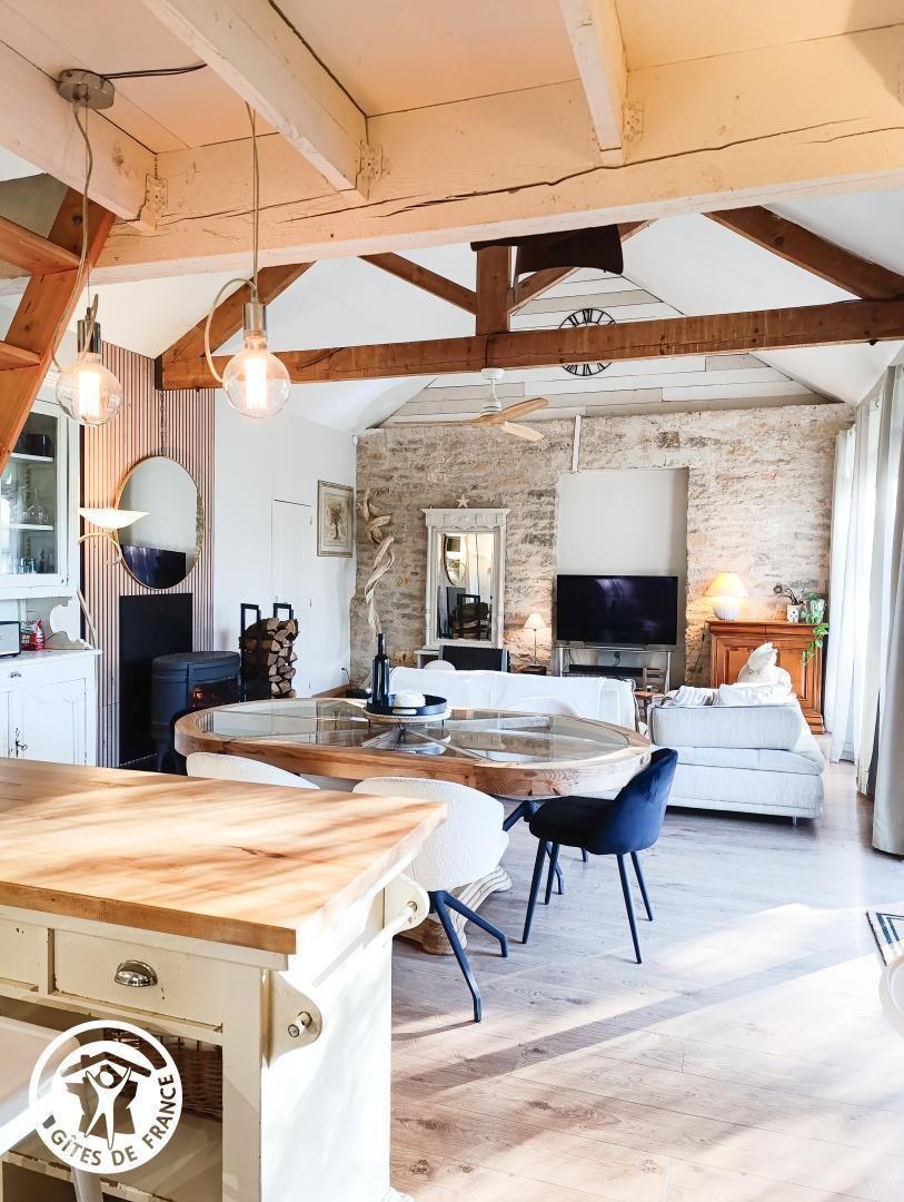 A spacious living area with a stone wall, a fireplace, a large TV, and a wooden dining table.