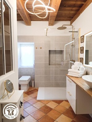 Een moderne badkamer met douche, toilet en wastafel.