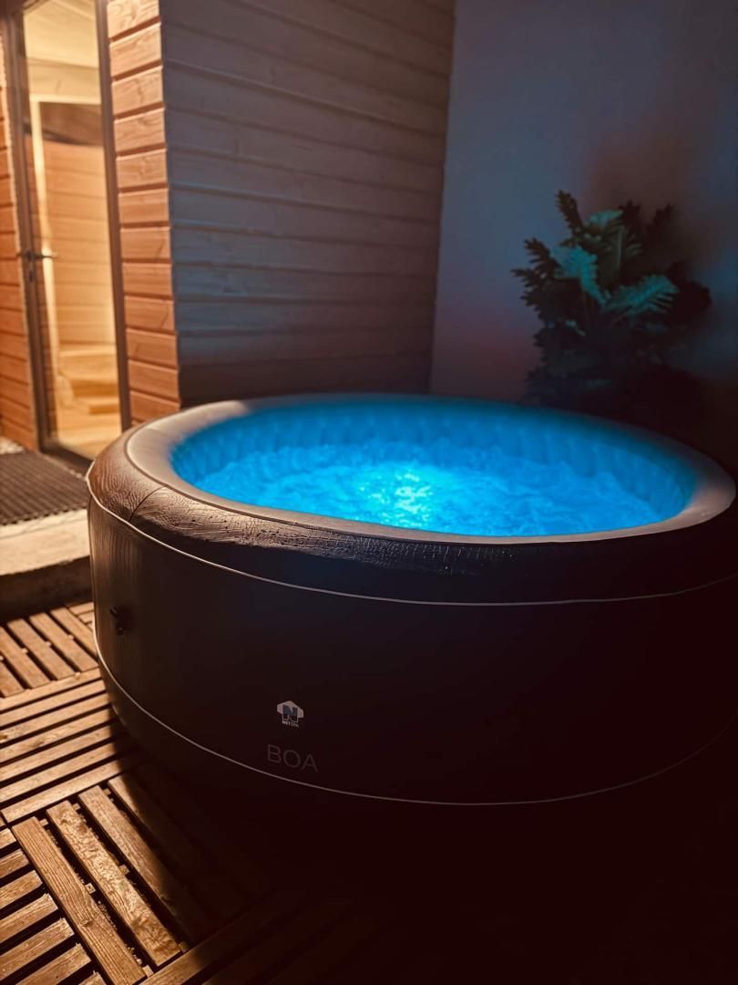 A hot tub with a visible logo, surrounded by wooden decking and a potted plant.