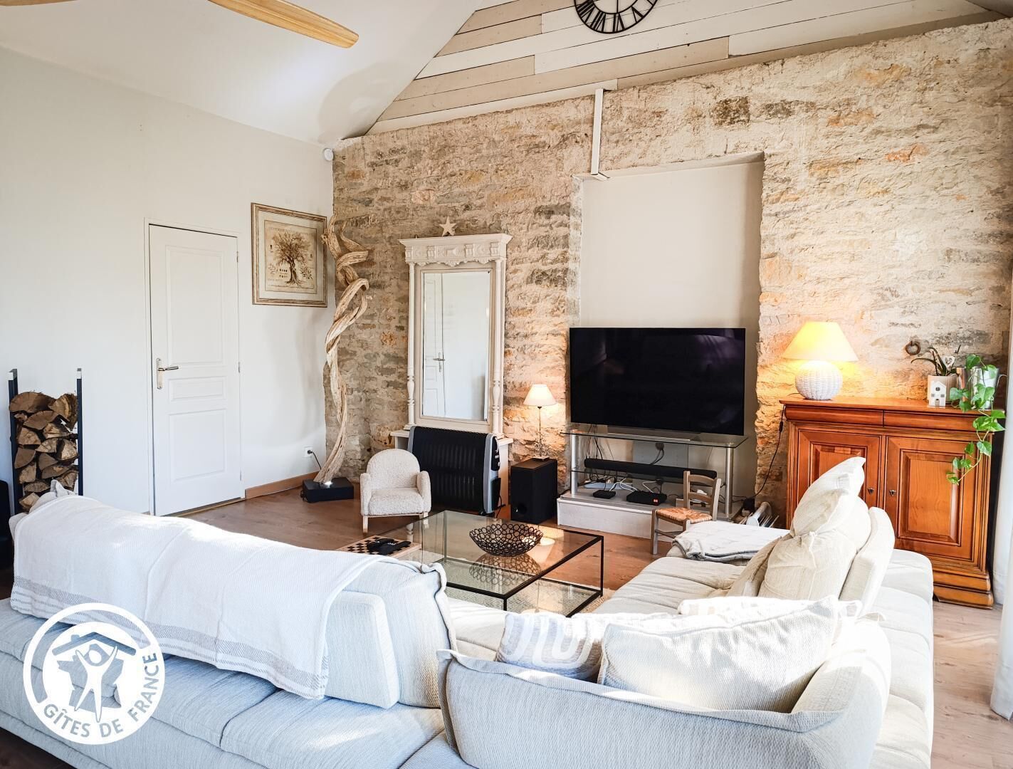 Una sala de estar con pared de piedra, chimenea, televisor y sofá.